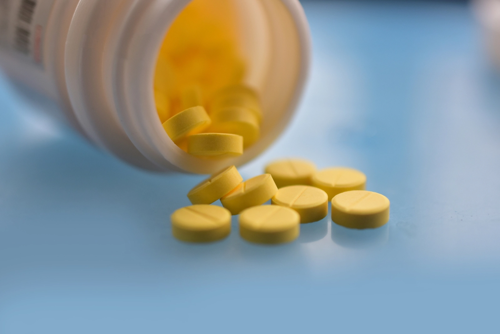 How Long Does Meloxicam Stay In Your System? A bottle of yellow pills open on its side.